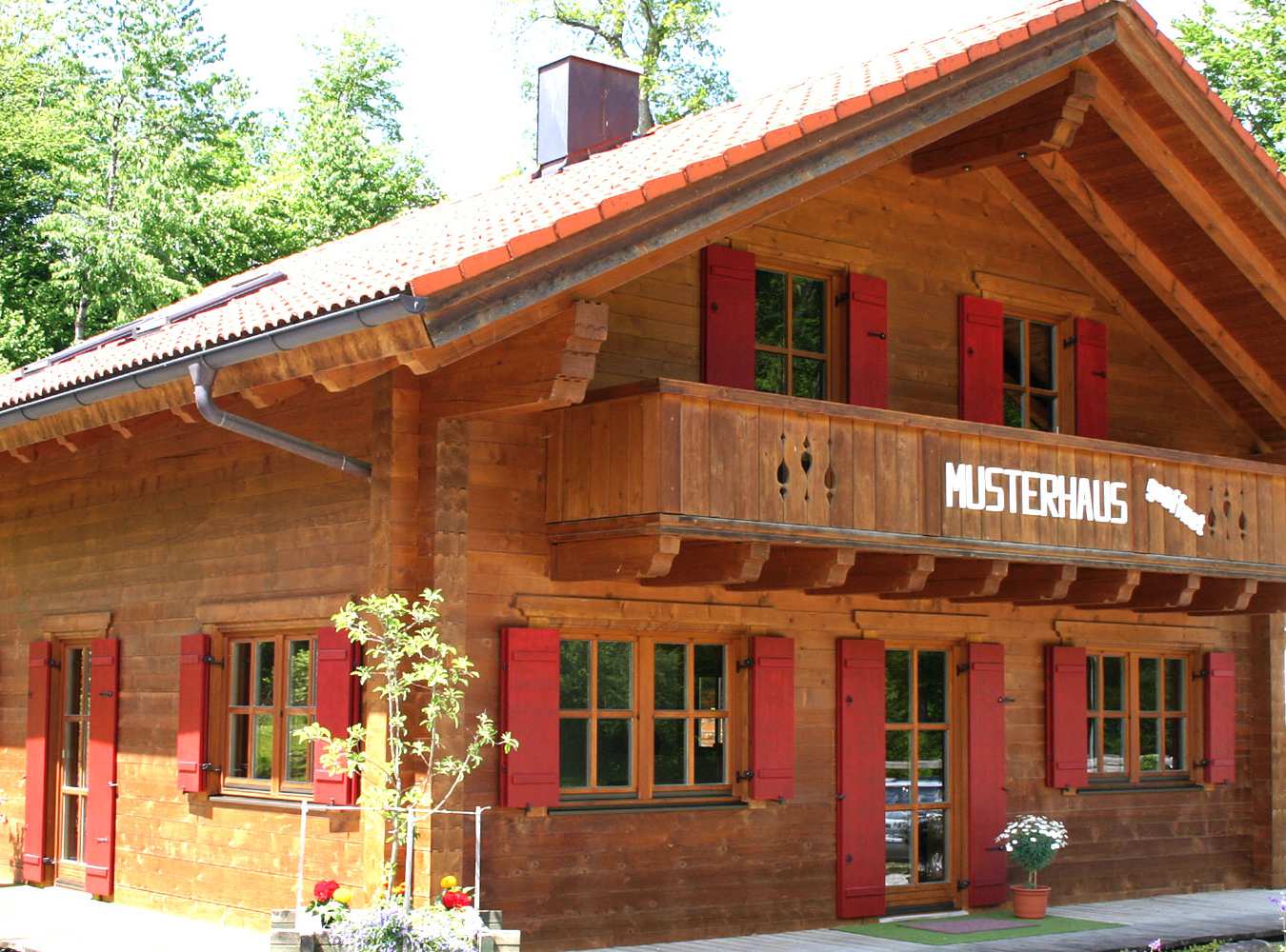 Musterholzhaus mit Balkon und roten Fensterläden 