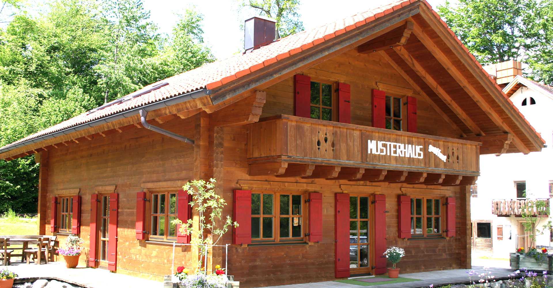 Musterholzhaus mit Balkon und roten Fensterläden 